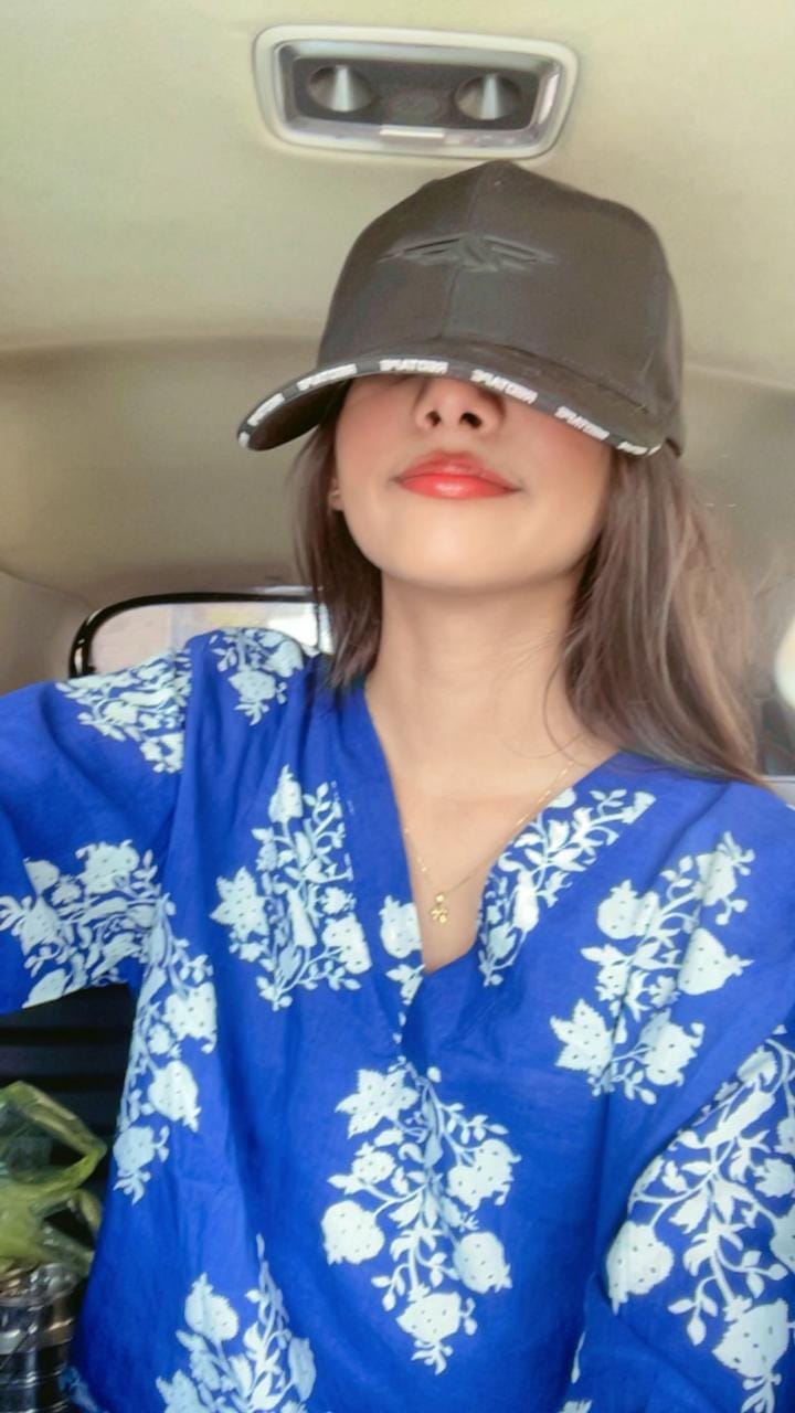 Kamya in a blue floral outfit and black cap