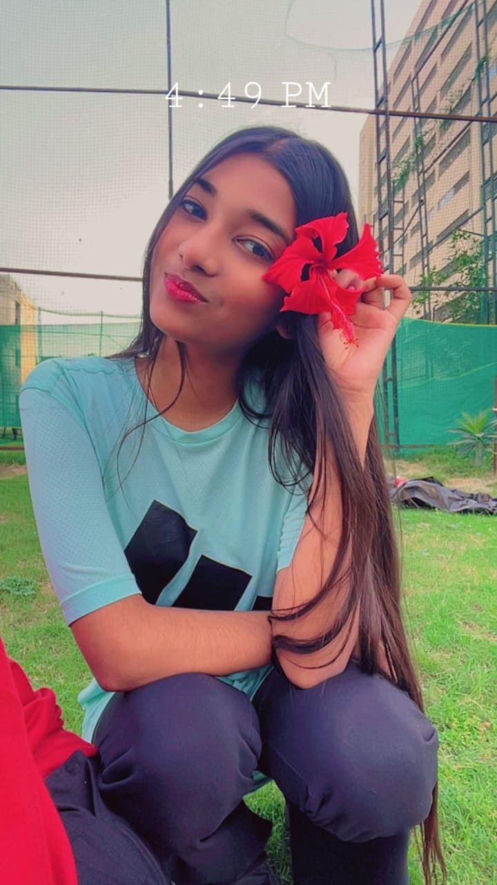 Kamya holding a red hibiscus flower